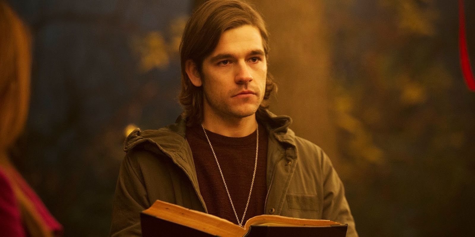 Quentin holds a book open in The Magicians.