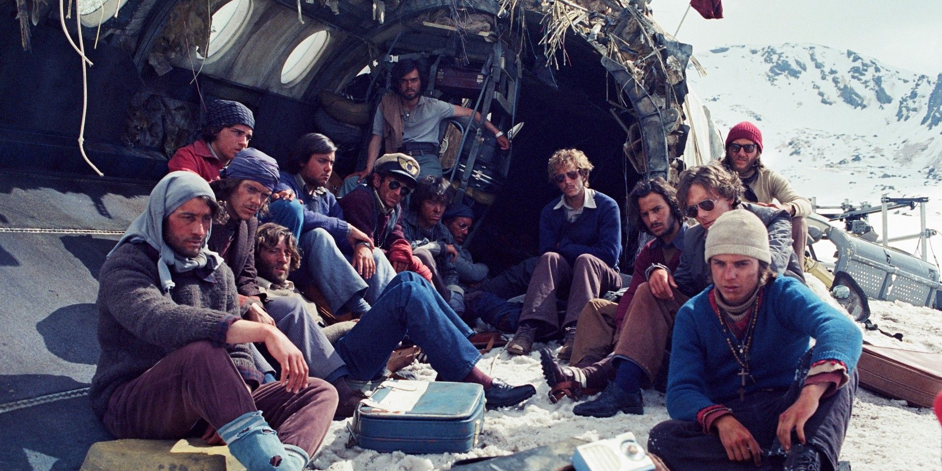 os sobreviventes sentados dentro e ao redor da fuselagem quebrada em Society of the Snow