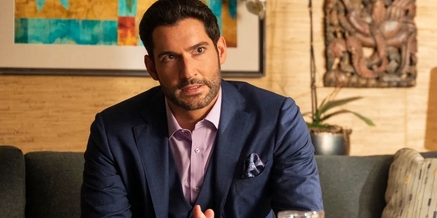 Tom Ellis as the titular protagonist sitting on a couch and wearing a suit in Lucifer
