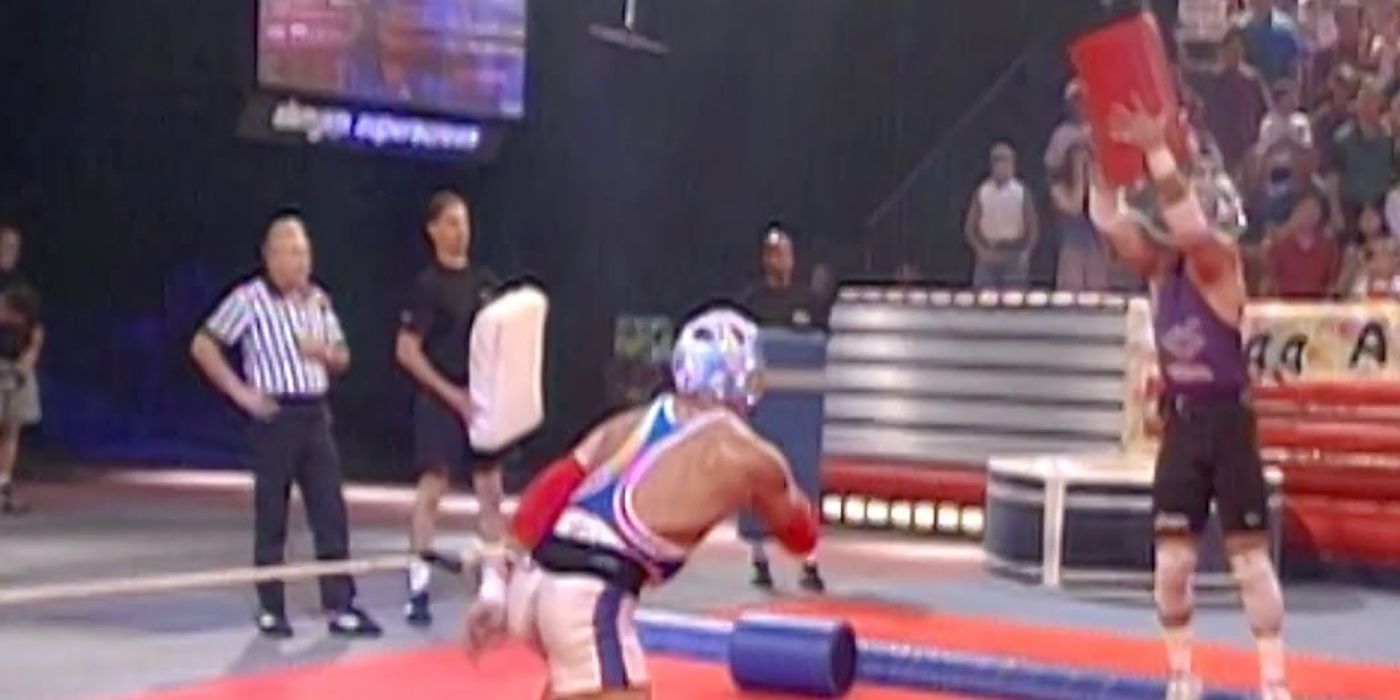 Dois homens competindo para agarrar grandes cilindros com cordas presas às costas no Snapback em American Gladiators.-1