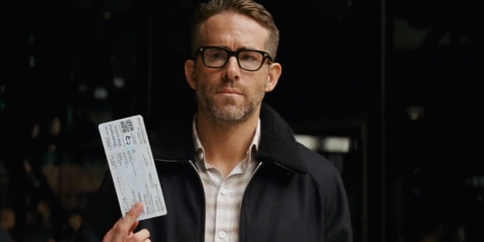 Ryan Reynolds holding up a ticket as Harry Goodman in Detective Pikachu