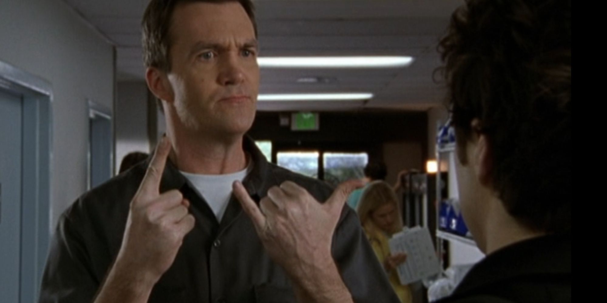 Neil Flynn as the Janitor in Scrubs holding up an index finger on one hand and his thumb and pinky on the other