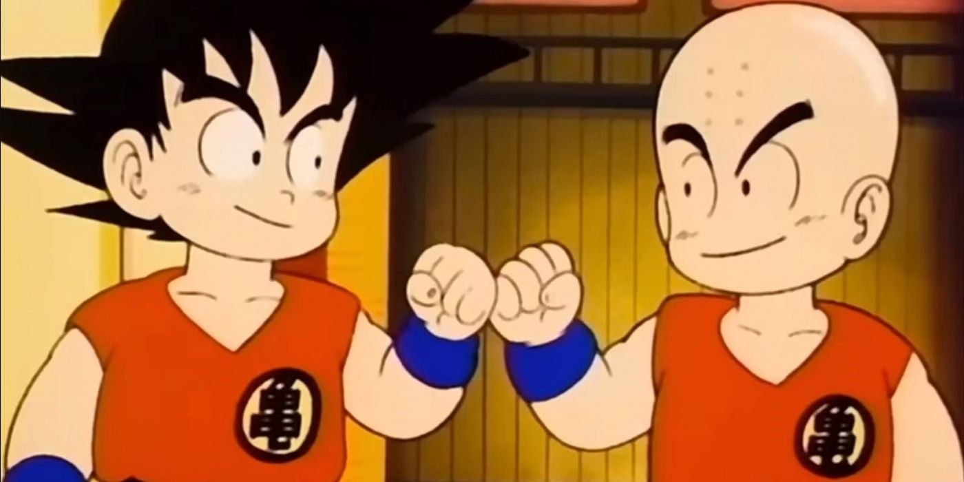 Young Goku and Krillin dapping each other up with smiles on their faces