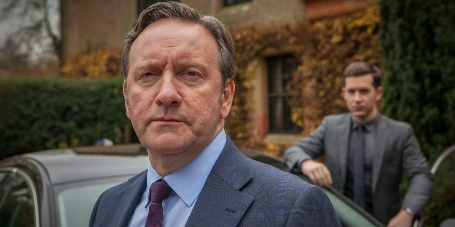 John Barnaby (John Nettles) standing in front of a car in Midsomer Murders.