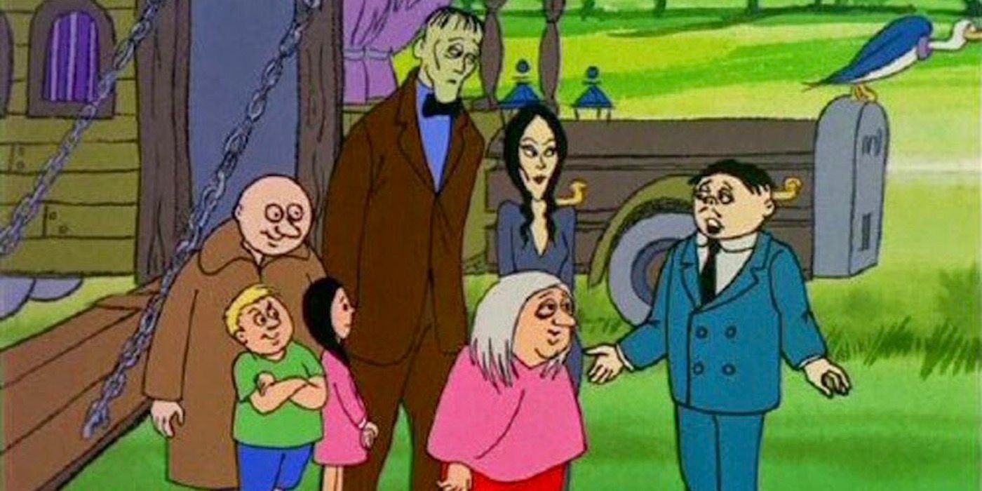 The Addams family is standing in front of their Victorian-style camper. 