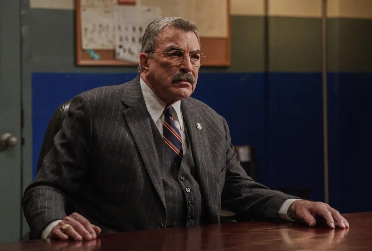 Tom Selleck sitting behind a table in Blue Bloods 