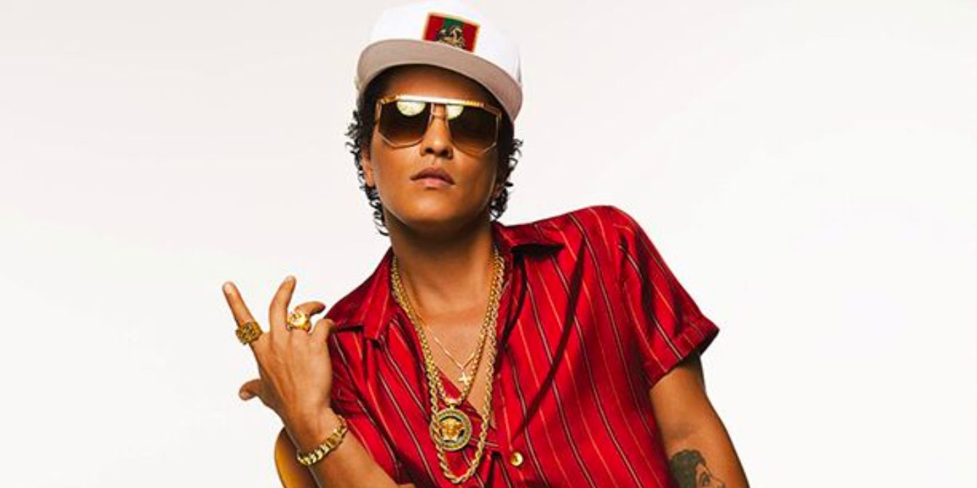 Bruno Mars wearing sunglasses and holding up his hand