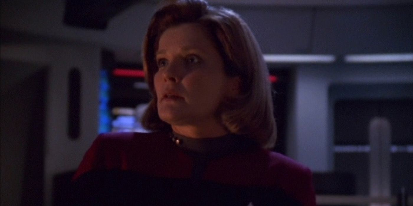 Capitão Janeway parado na ponte Voyager durante alerta vermelho