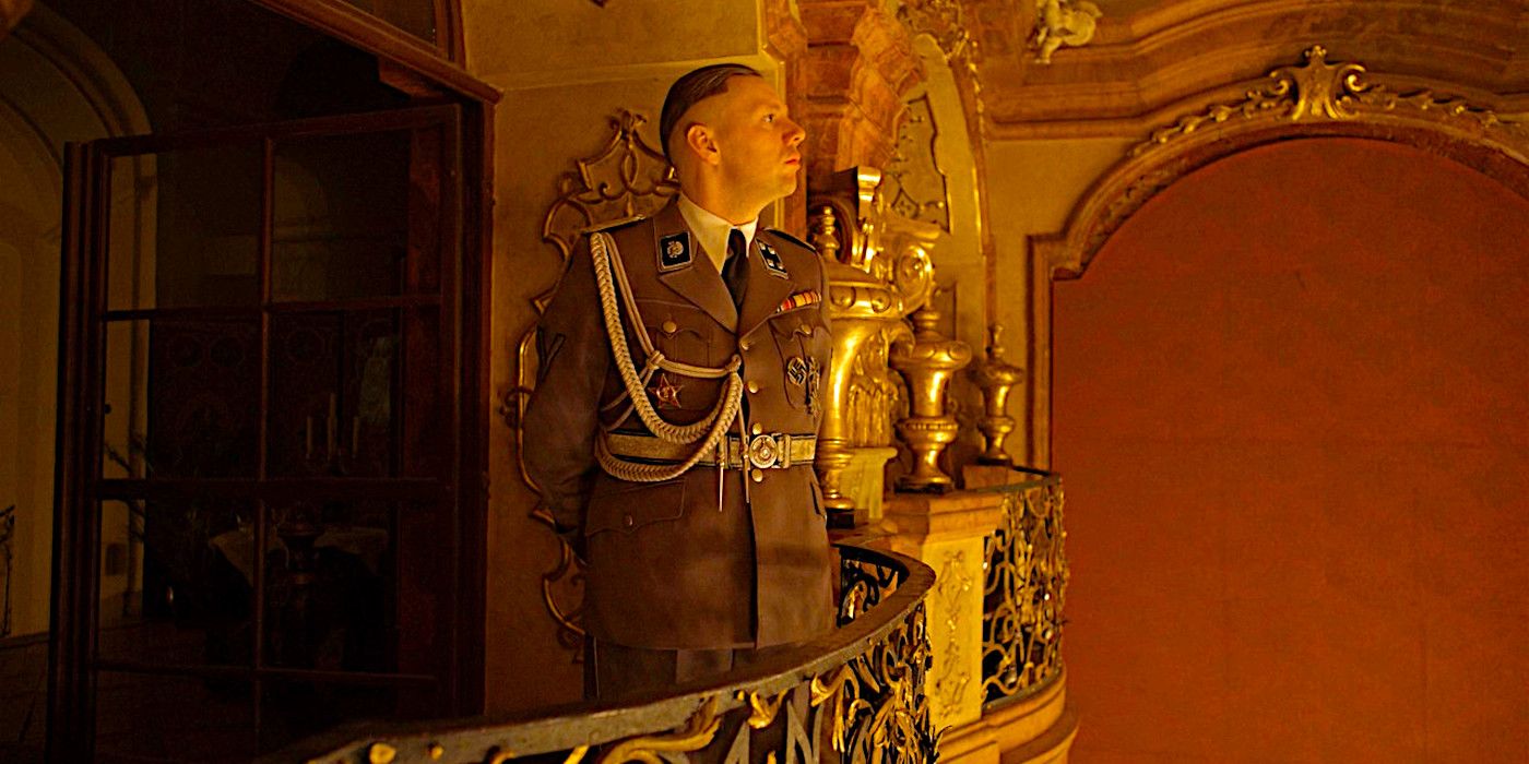 Christian Friedel in a Nazi uniforn gazing across a large, ornate theater from a balcony in a scene from The Zone of Interest