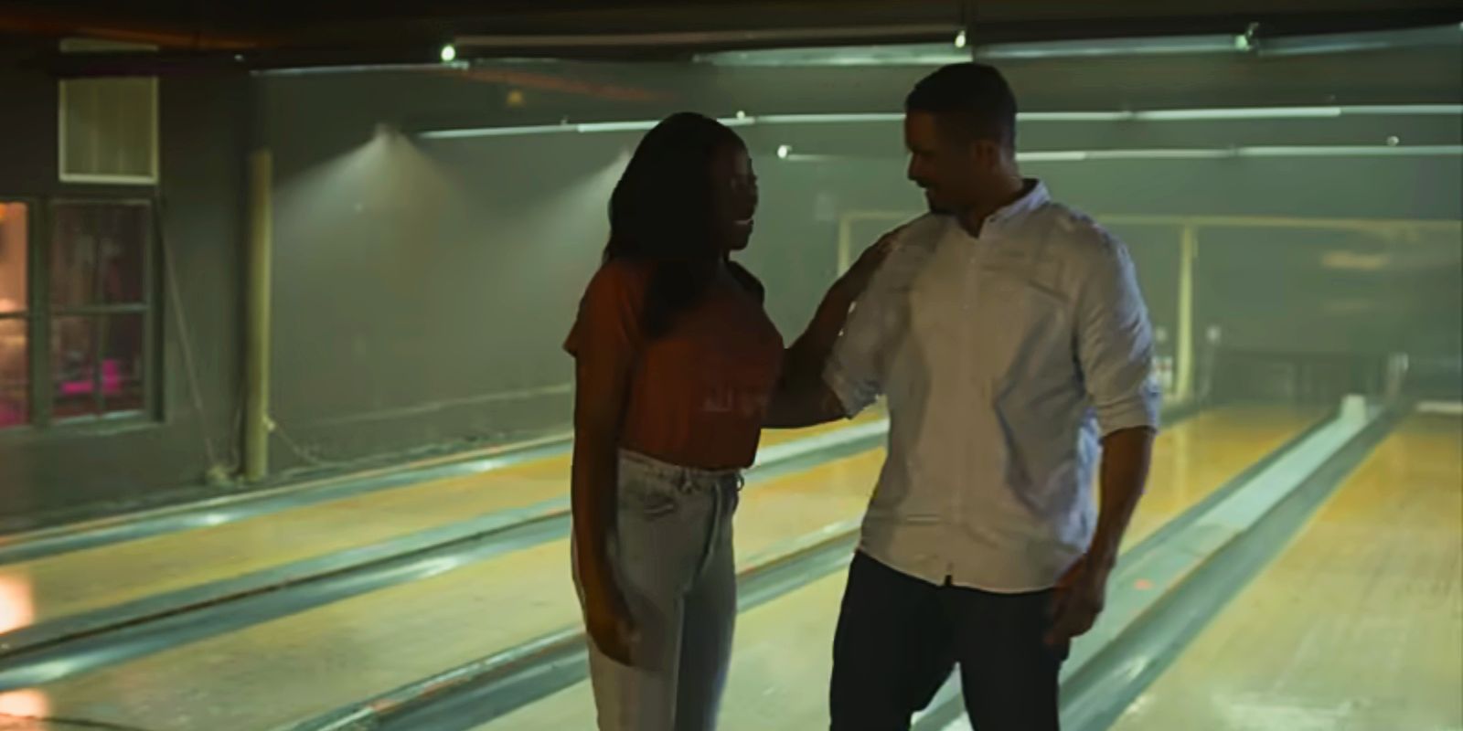 Claire and Adam look at each other smiling in a bowling alley in Players