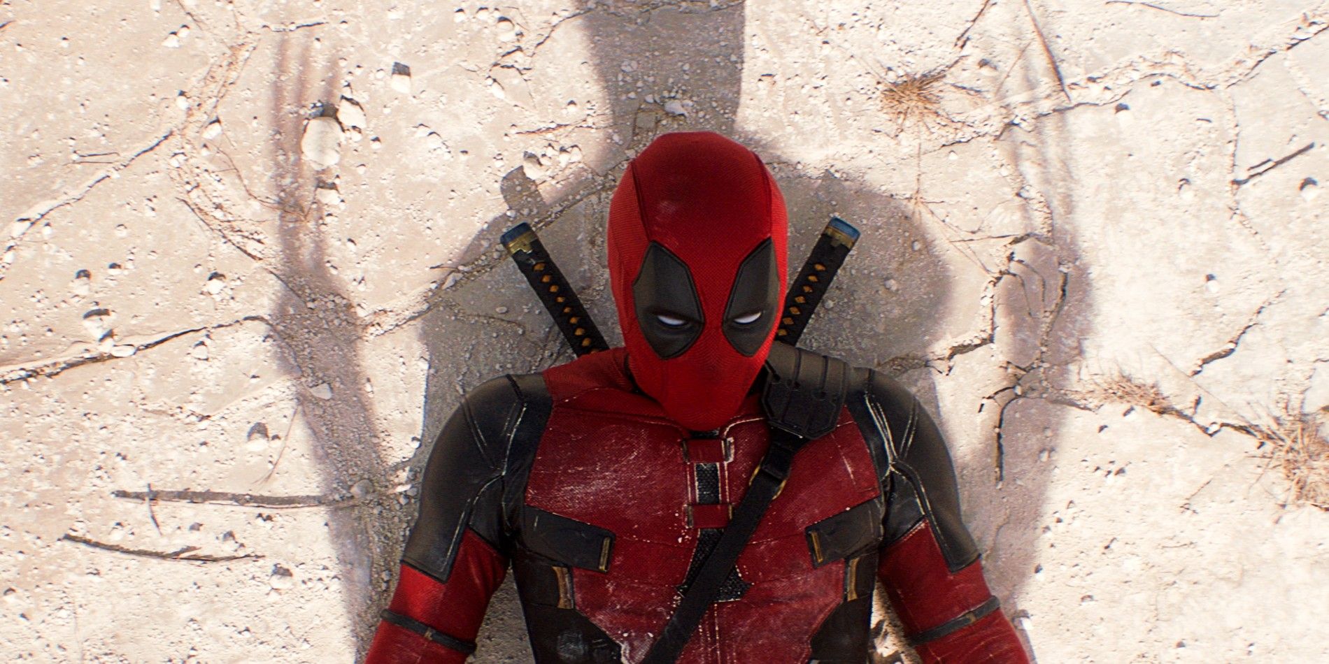 Close Up On Ryan Reynolds As Deadpool Laying Down On Dry Ground Covered By Shadow of Wolverine And His Claws In Deadpool and Wolverine