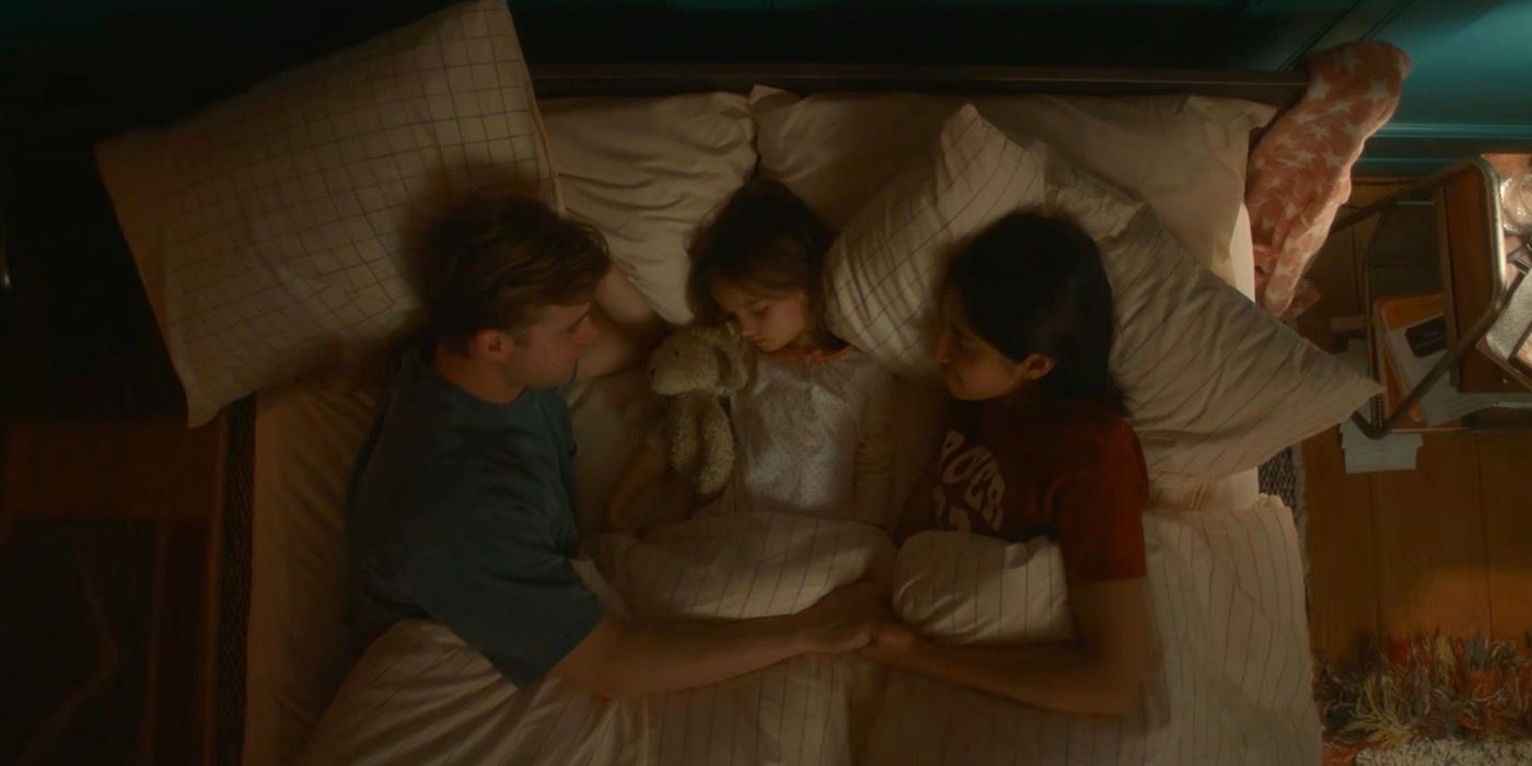 Dexter and Emma hold hands as Jasmine is lying in between them. 