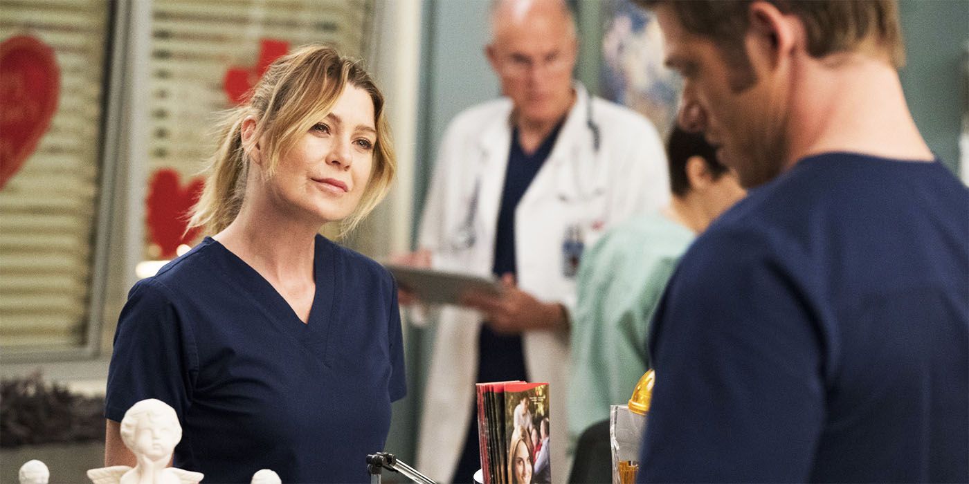 Ellen Pompeo talking to another doctor as Meredith in her navy blue scrubs in Grey's Anatomy