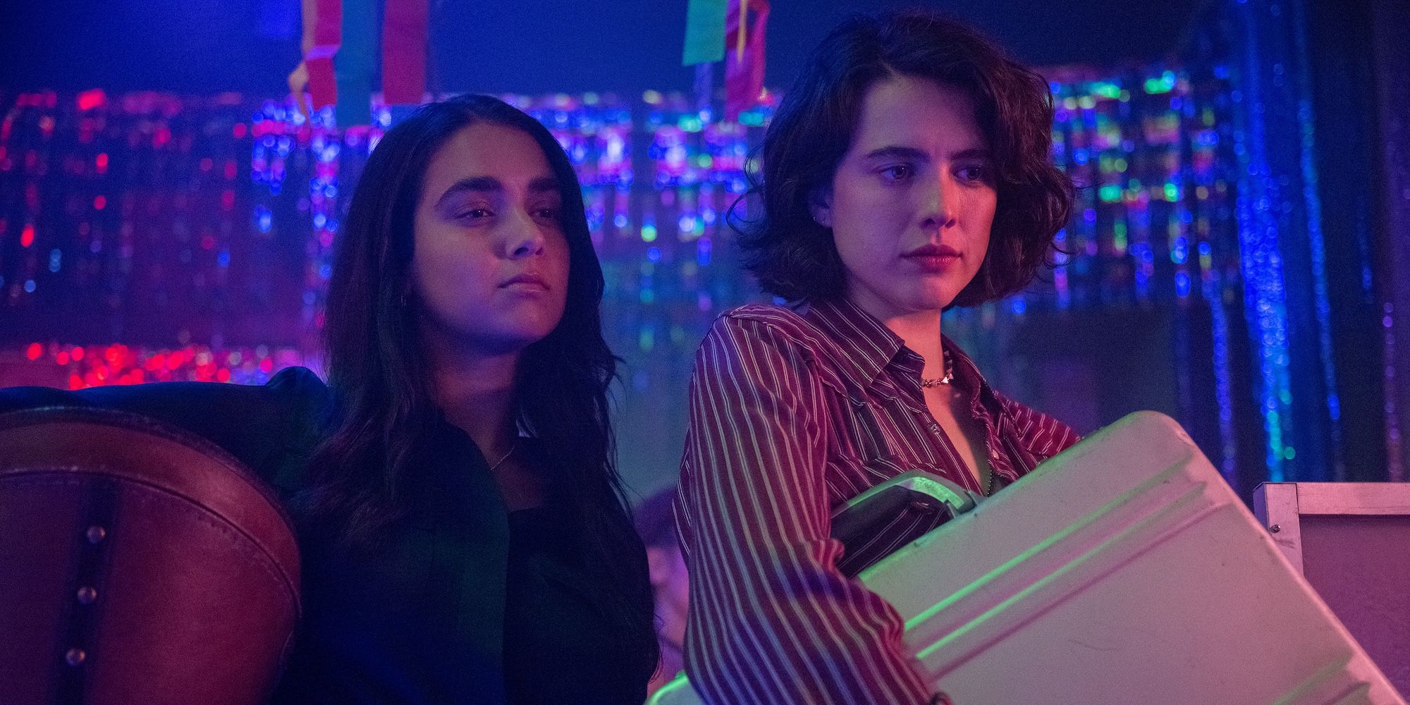 Geraldine Viswanathan and Margaret Qualley hold a suitcase away from someone in Drive-Away Dolls