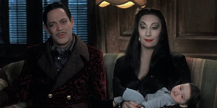 Gomez and Morticia sitting with baby Pubert on the sofa in Addams Family Values