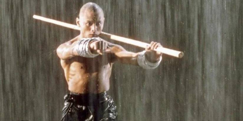 Gordon Liu as Monk San Te trains in the rain with Wushu rings and a bo staff in The 36th Chamber of Shaolin.