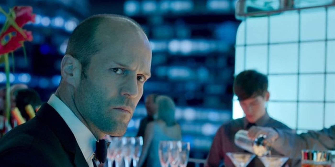 Jason Statham sitting a bar reflected by blue light