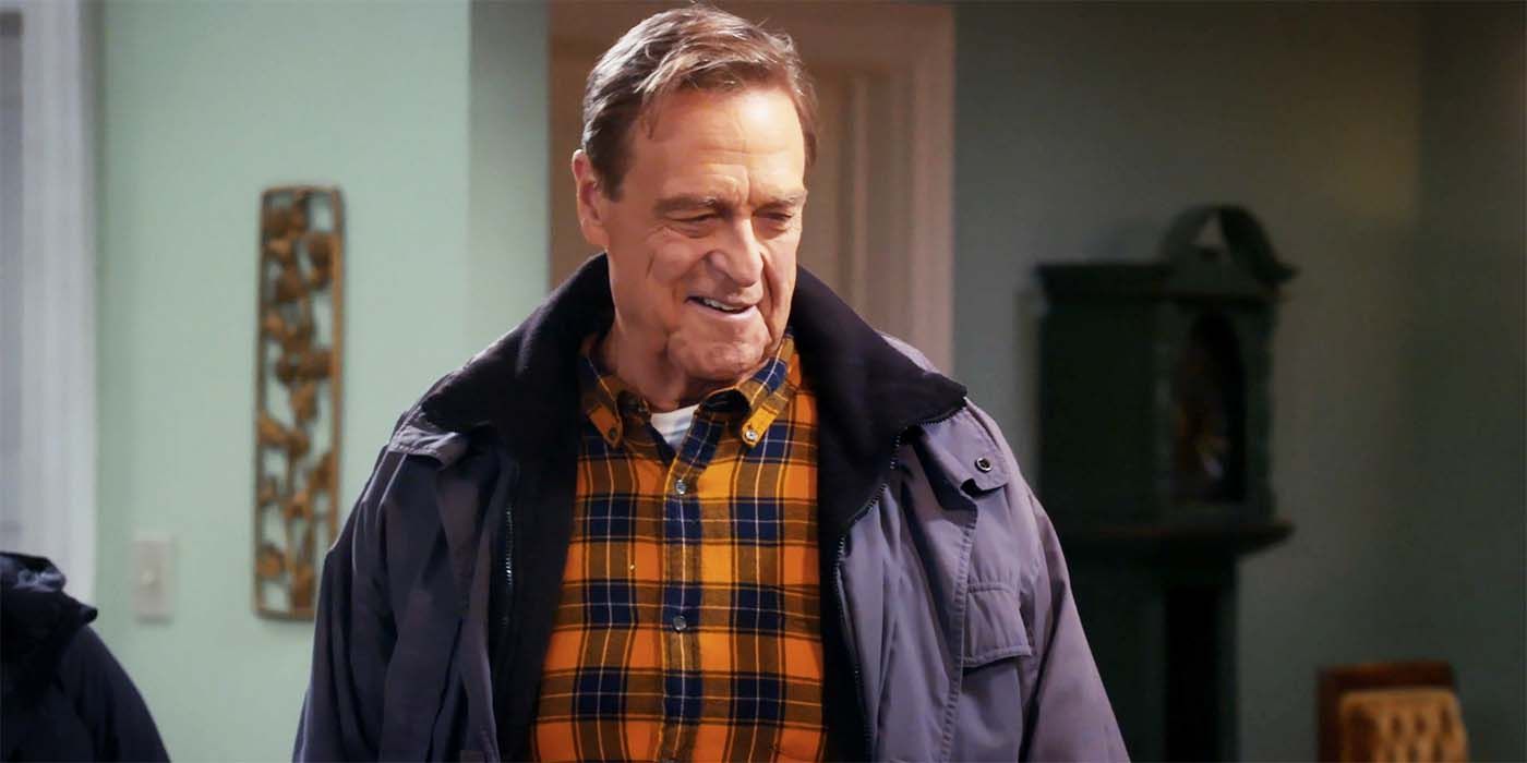 John Goodman olhando para baixo e sorrindo na 6ª temporada de The Conners