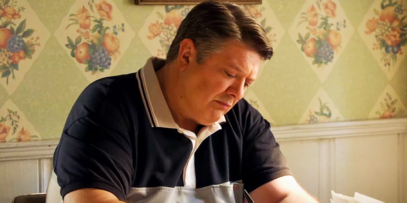 Lance Barber as George sitting at a table in Young Sheldon
