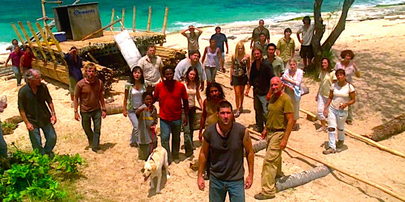 Vários membros do elenco de Lost dispostos em uma praia arenosa olhando para algo