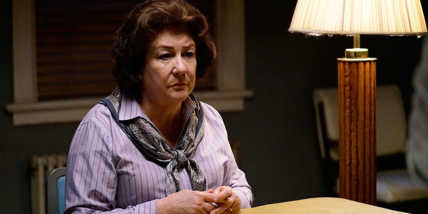Margo Martindale sitting at a table with her fingers clasped together. 