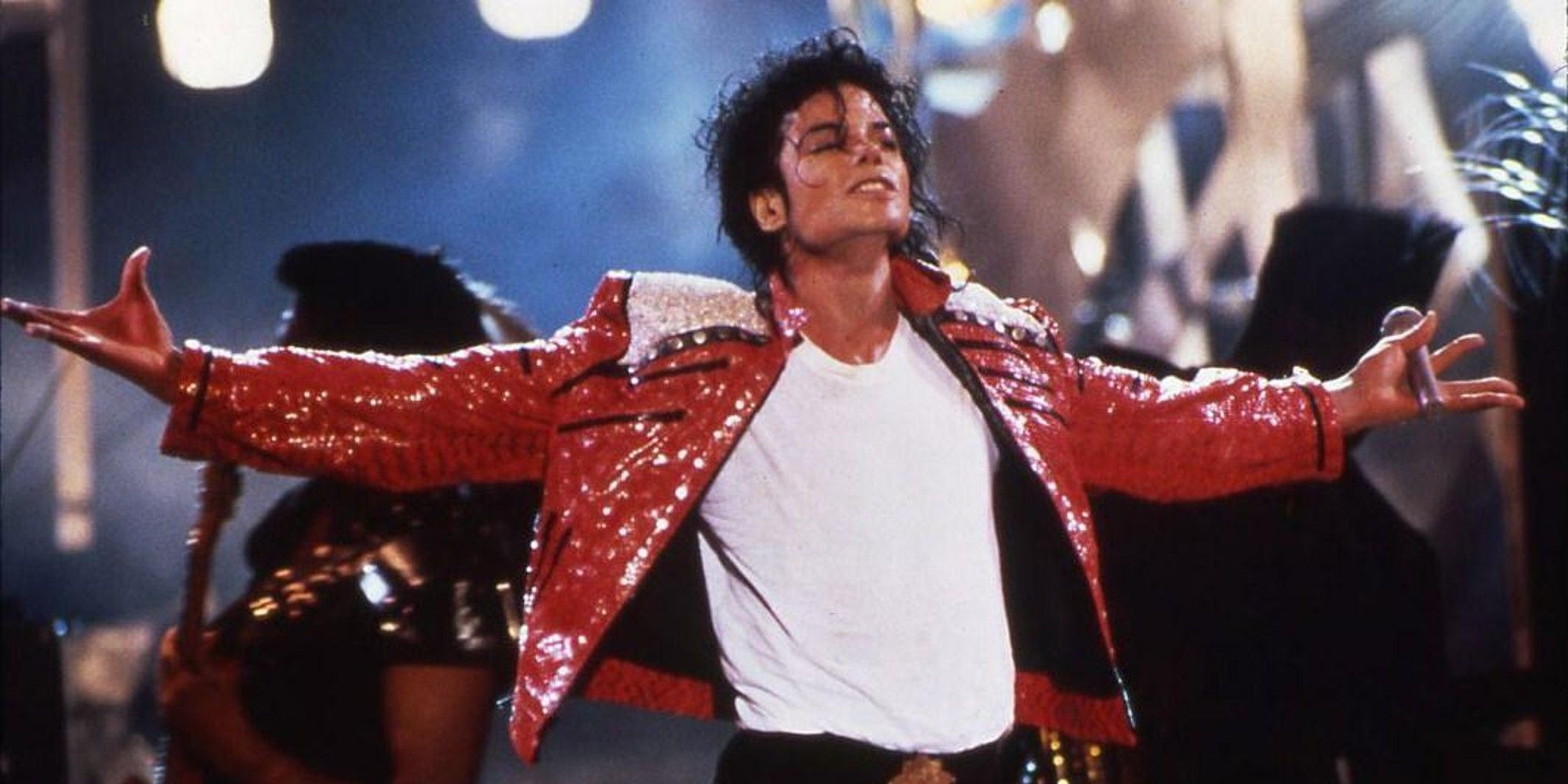 Michael Jackson with his arms open wide performing Beat It