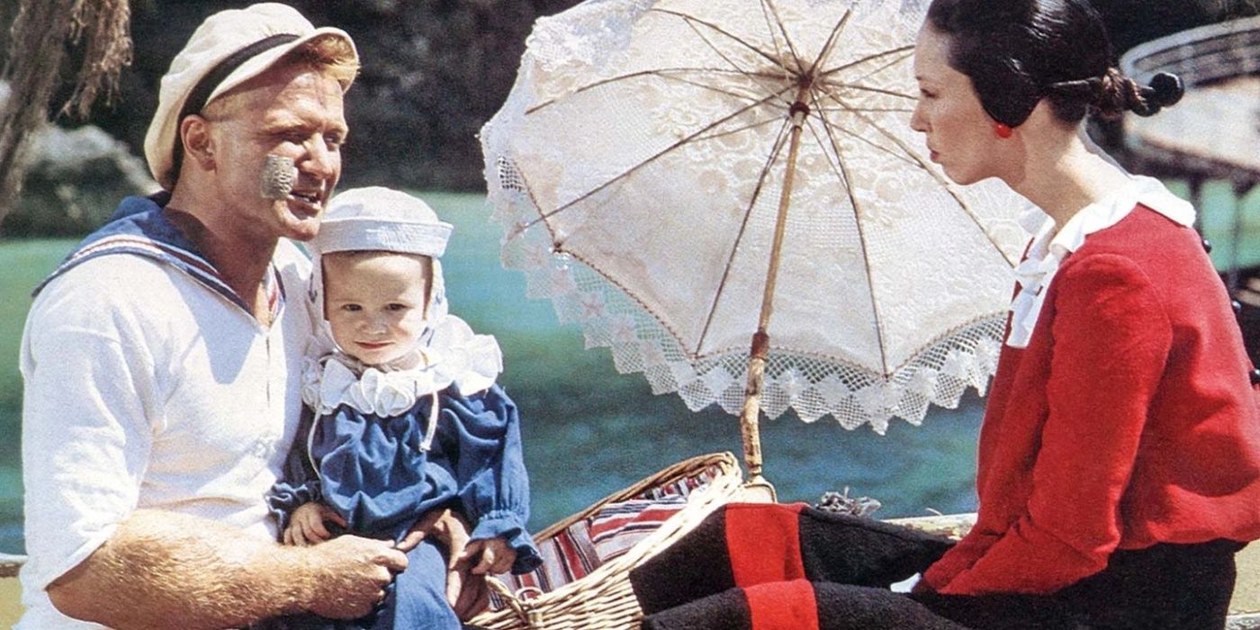 Popeye (Robin Williams) holding his child on a boat in Popeye