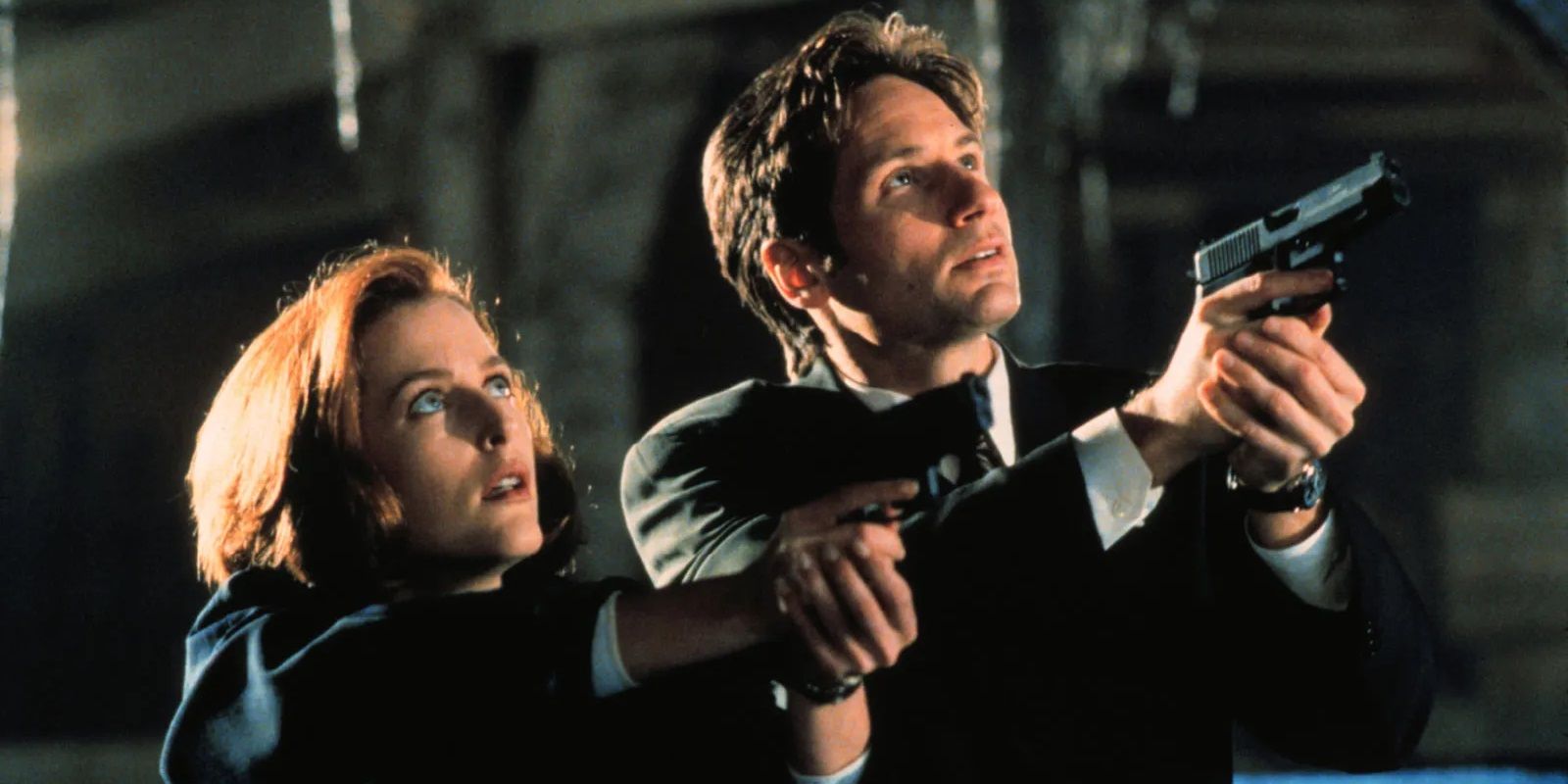 Mulder (David Duchovny) and Scully (Gillian Anderson) point their guns up toward the sky in The X-Files