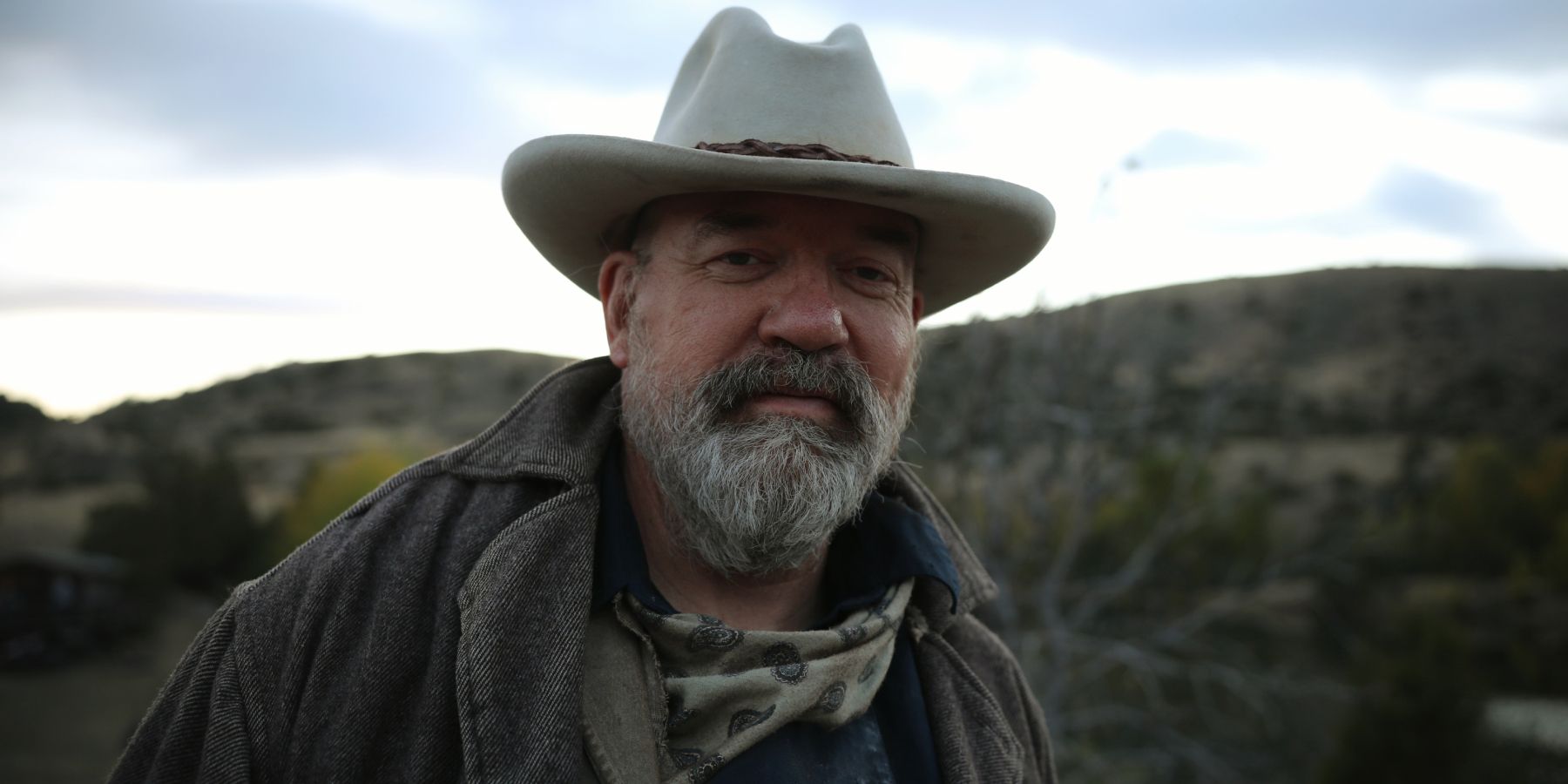 John Carroll Lynch está em frente a uma montanha em Outlaw Posse