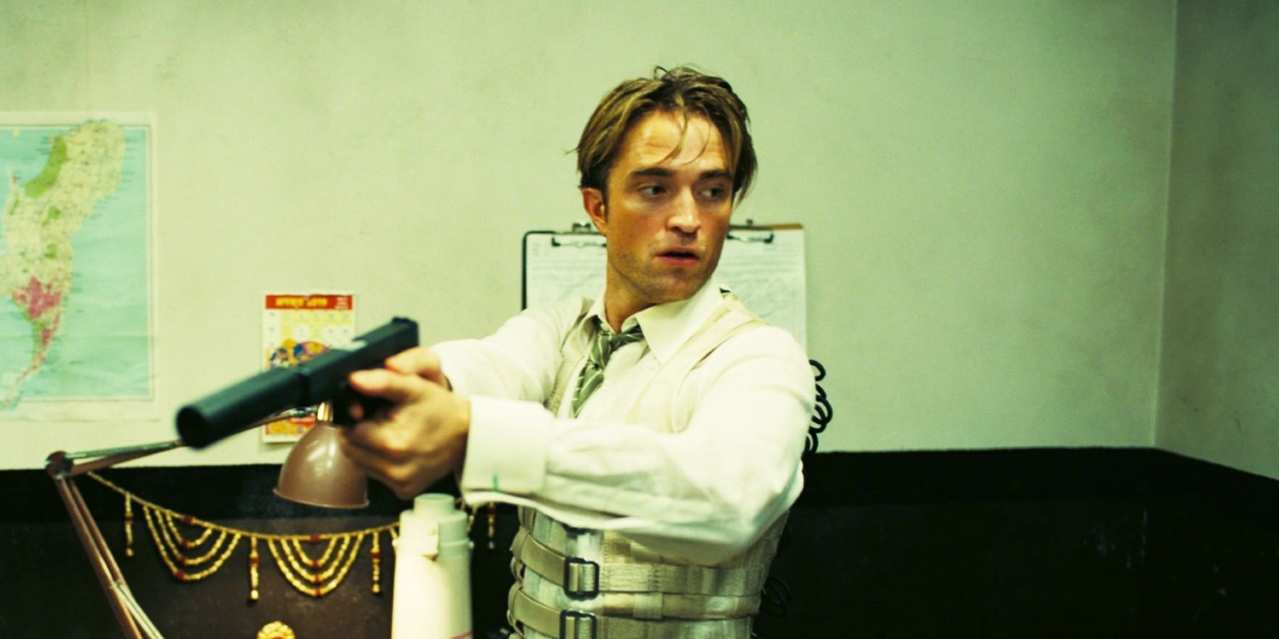 Robert Pattinson pointing a gun as Neil in Tenet