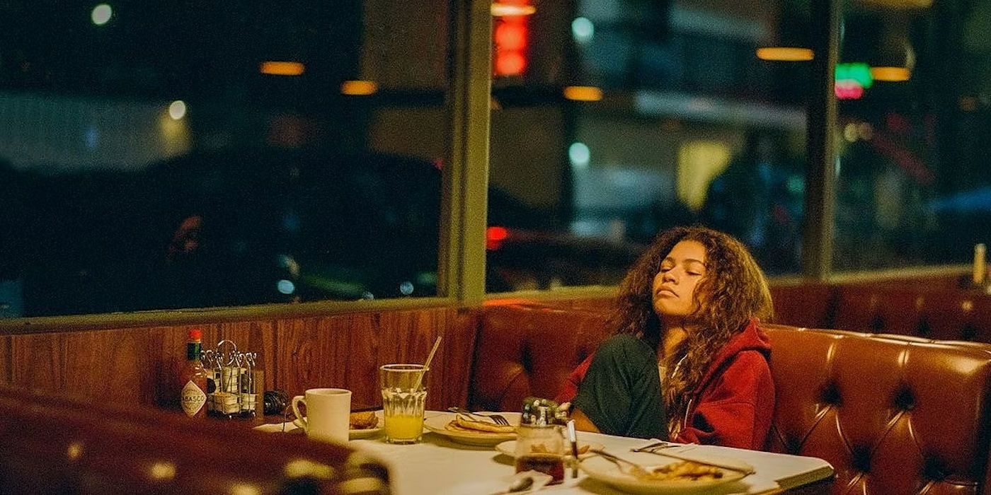 Zendaya with her eyes closed as Rue in a diner booth in Euphoria