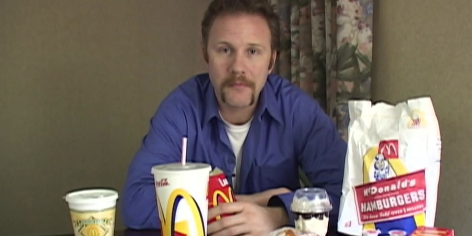 Morgan Spurlock sentado em uma mesa no documentário Supersize Me