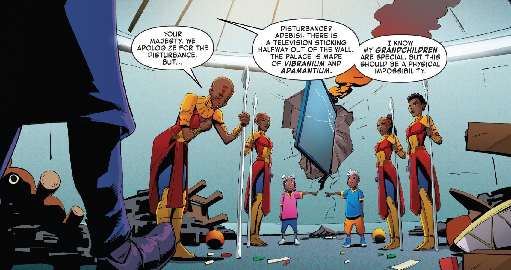 Four Dora Milaje women wielding spears and in ceremonial robes flank two small children (a boy and a girl), each pointing at the other. A broken widescreen television juts out of the wall between them, wrecked and smoking. Adebisi, the head of the Dora Milaje, apologizes, while T’challa (entering the panel) comments on how the wall is made of Vibranium and Adamantium; shattering it like this shouldn’t even be possible.