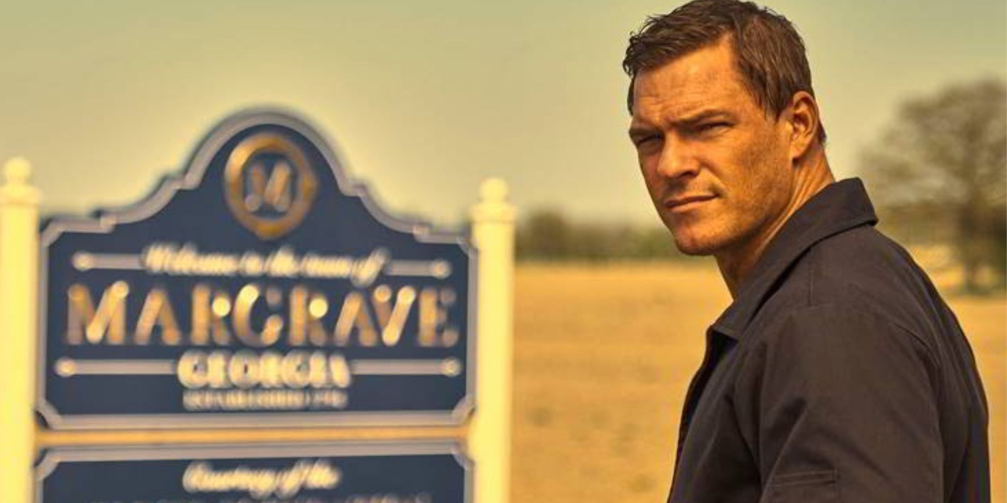 Alan Ritchson as Reacher near the sign for Margrave, Georgia in Reacher season 1