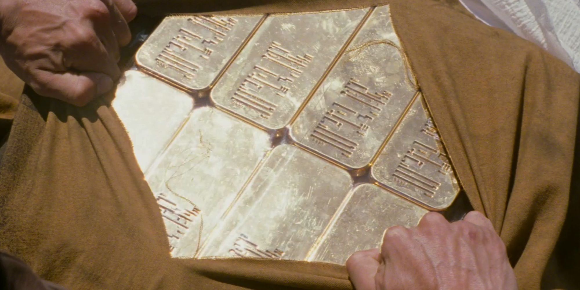 Clothes being parted to reveal a lot of gold bars in Looper