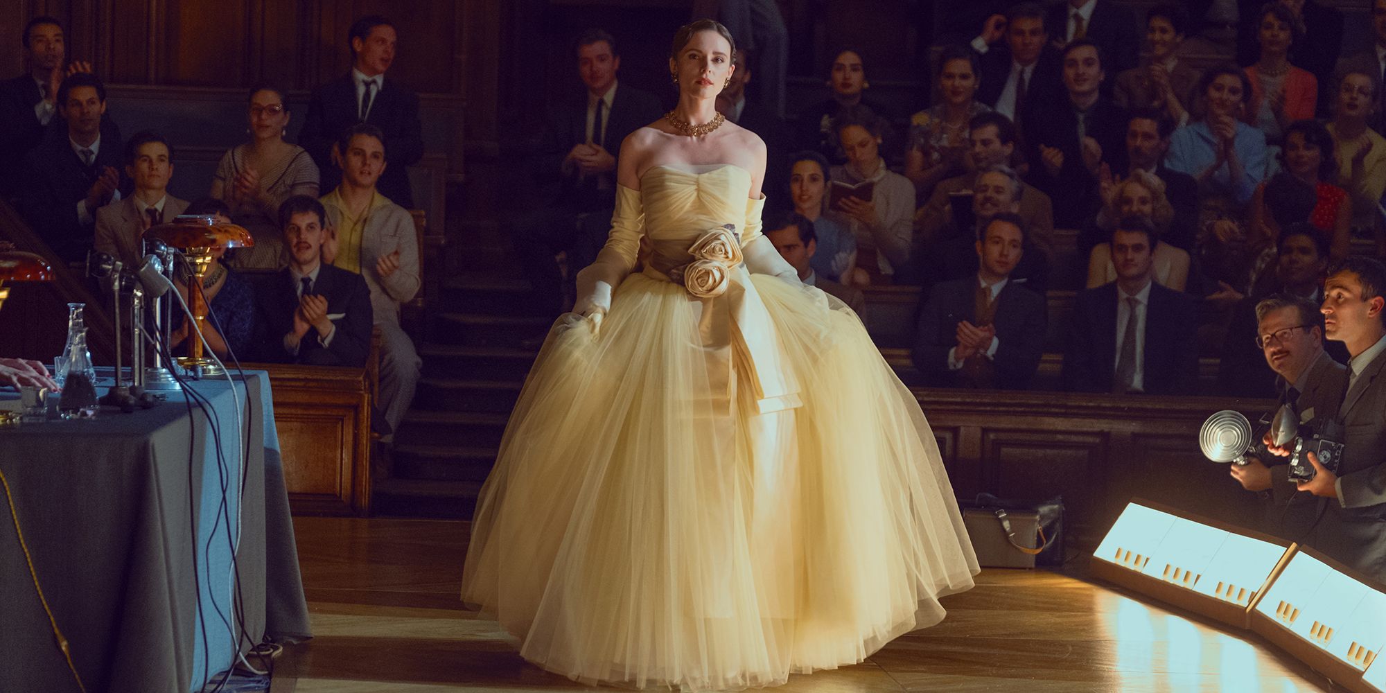 Woman modeling a yellow Dior gown to a crowd in The New Look
