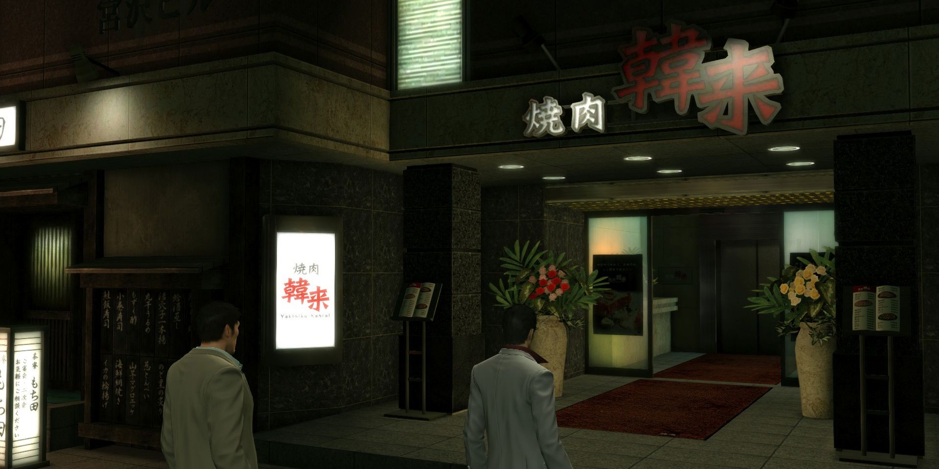 Kiryu outside Kanrai at night in a screenshot from the Yakuza series.
