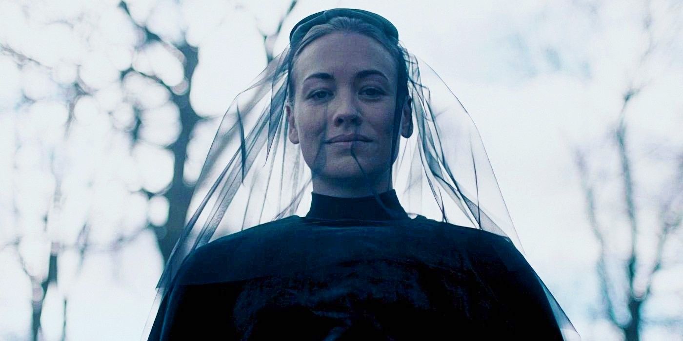 Yvonne Strahovski smiling serenly while looking downward while wearing funeral clothes in The Handmaid's Tale