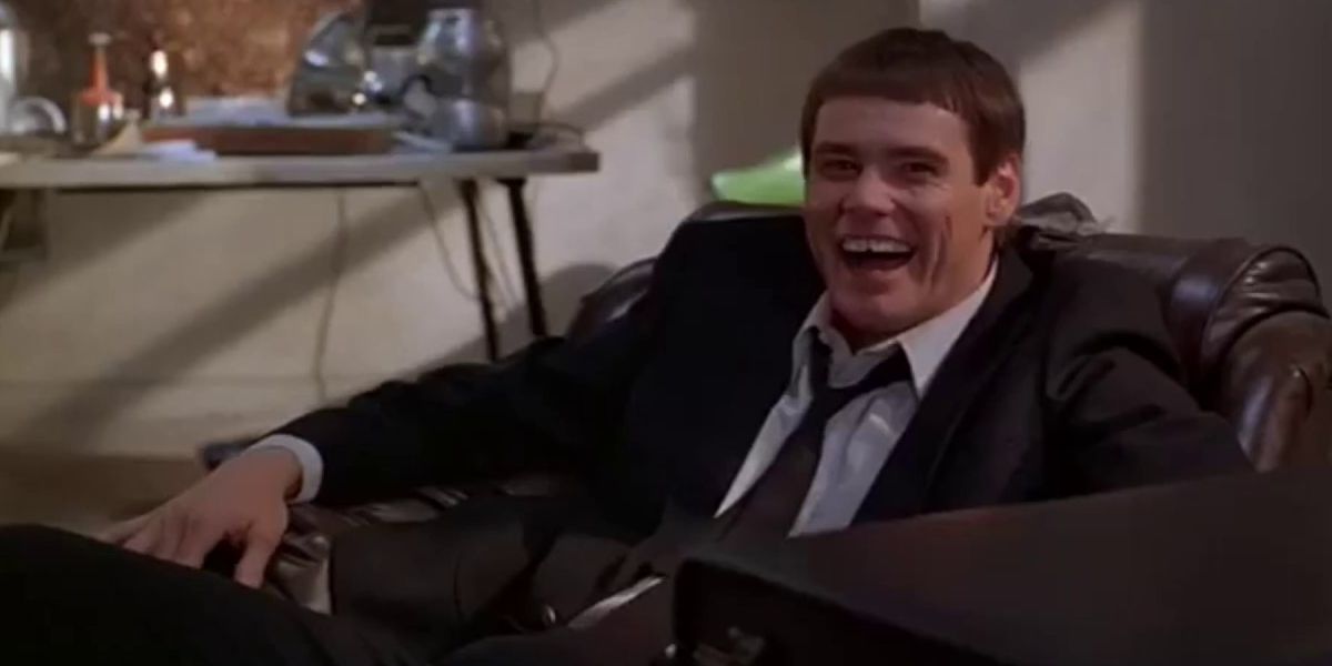 Jim Carrey sitting in a chair and laughing as Lloyd in Dumb and Dumber