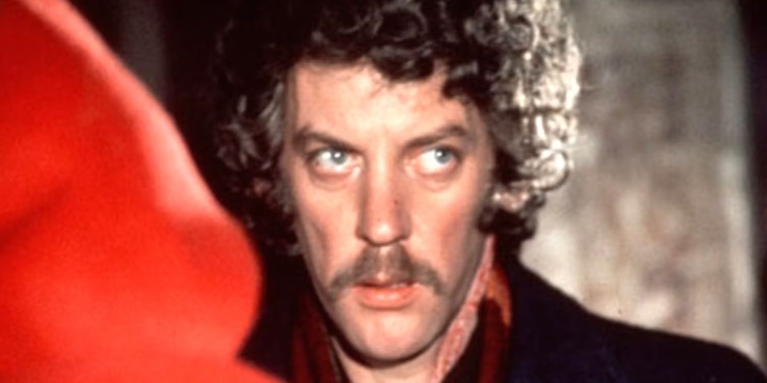 Donald Sutherland as John Baxter standing in front of the figure in the red coat in Don't Look Now