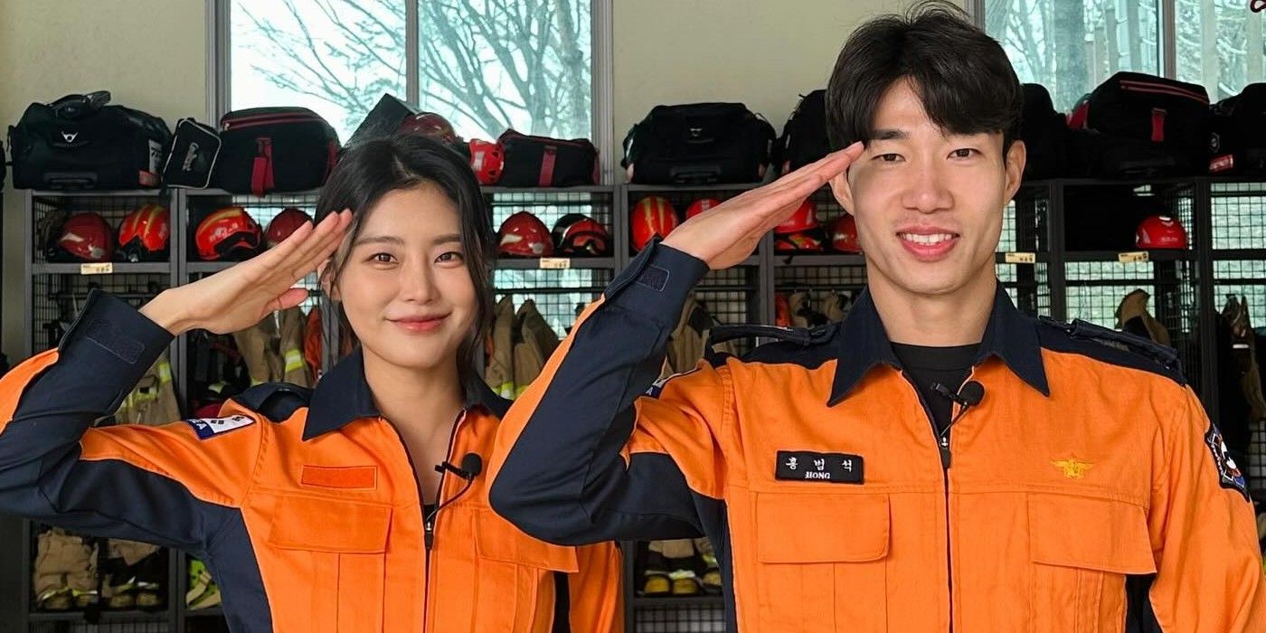 Hong Beom Seok e sua amiga Soyeon posam em posição de saudação vestindo uniformes laranja de bombeiro.