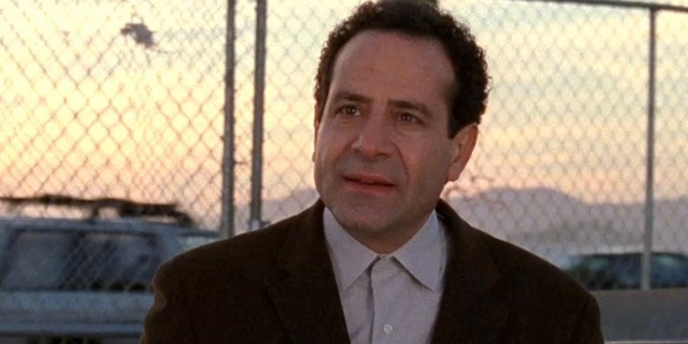 Adrian Monk is standing in front of a chain link fence looking angry in Monk