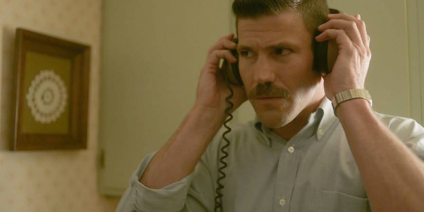 Peter Walsh (Austin Stowell) listening to someone through headphones in A Friend of the Family