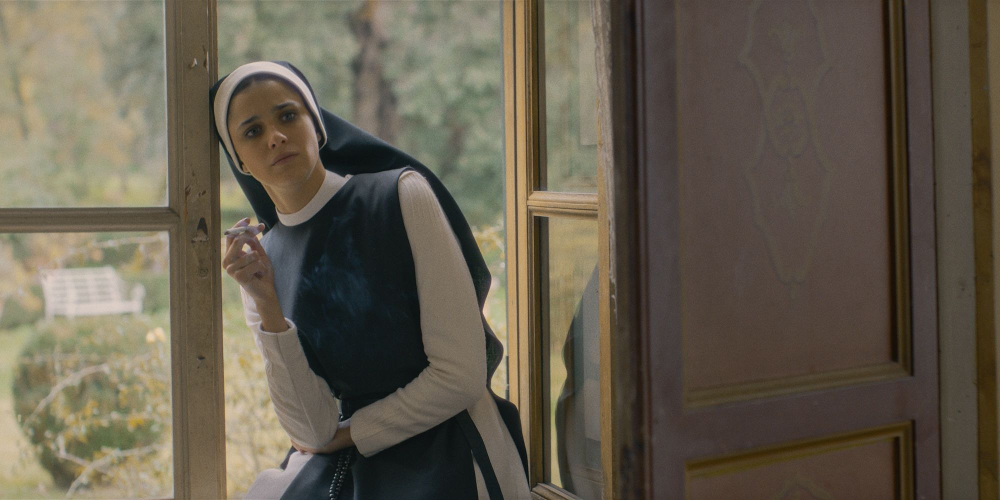 Benedetta Porcaroli as Gwen smoking near a window in Immaculate