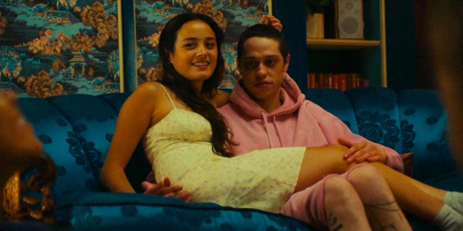 Emma (Chase Sui Wonders) and David (Pete Davidson) Sitting on the couch smiling in Bodies Bodies bodies