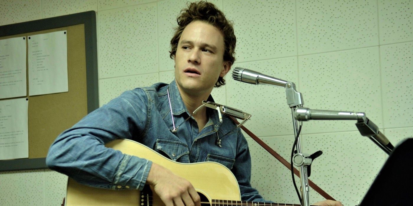 Heath Ledger playing the guitar and sitting behind a microphone.