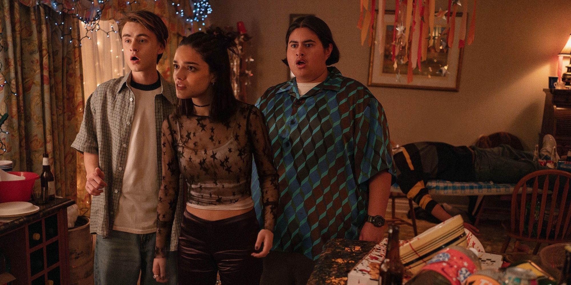 Jaeden Martell, Rachel Zegler, and Julian Dennison looking shocked at a house party in Y2K movie still
