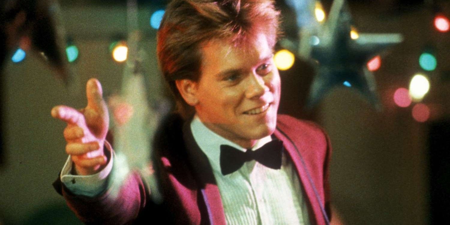 Kevin Bacon holding his arm out with a smile in Footloose