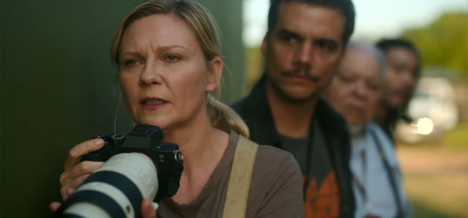 Kirsten Dunst holding a camera in Civil War with other reporters behind her