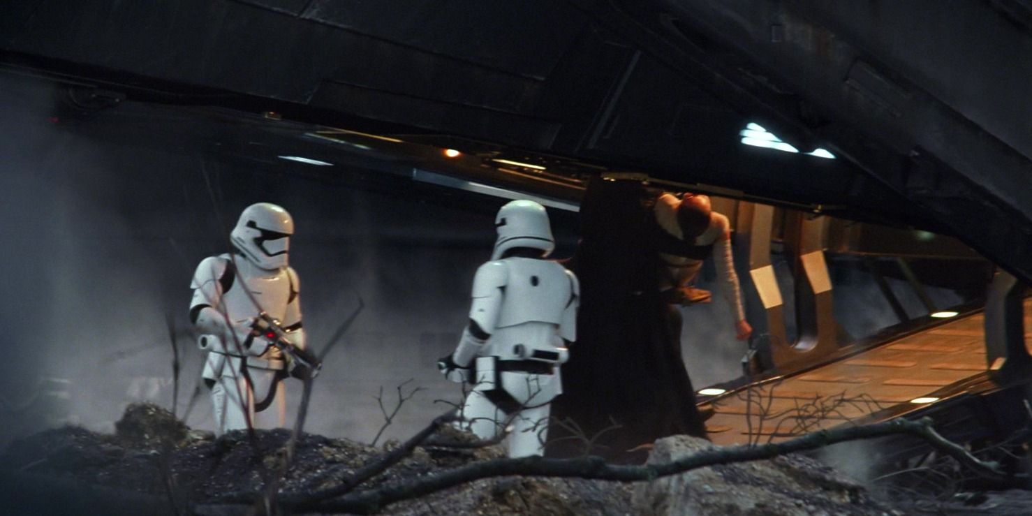 Kylo Ren carrying Rey up the ramp of his ship with stormtroopers looking on.